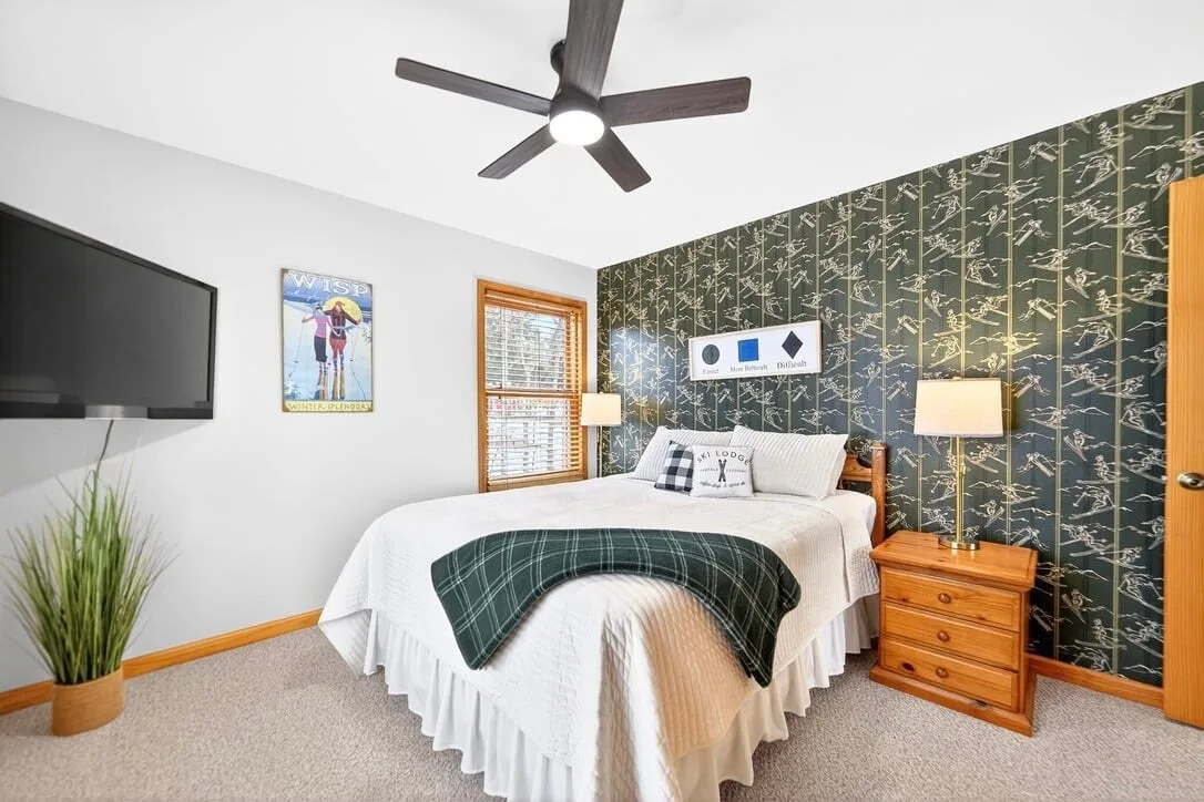 Bedroom with patterned green wallpaper and a wall-mounted TV