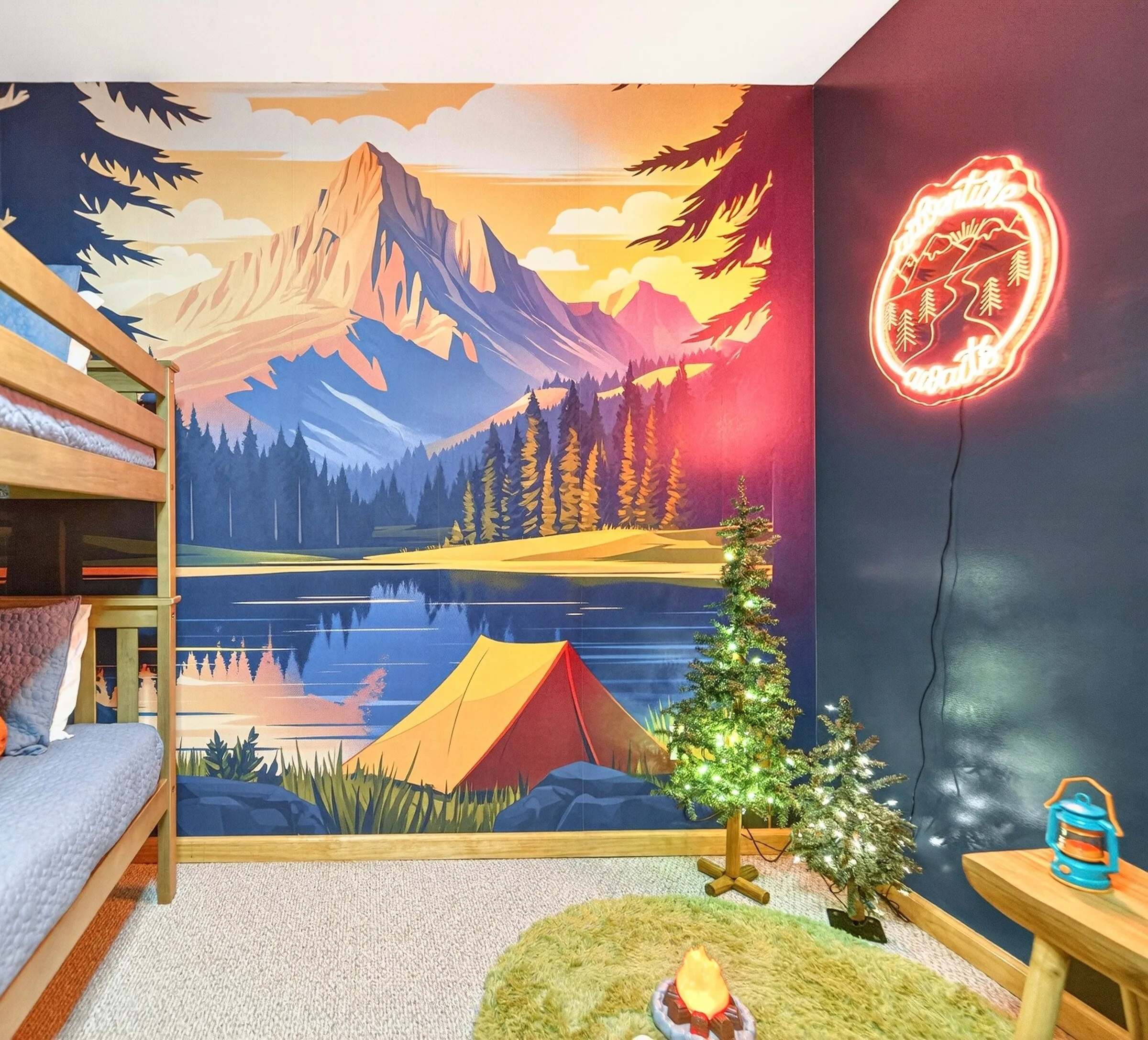 Bunk room painted with a mountain and lake mural and a neon campfire