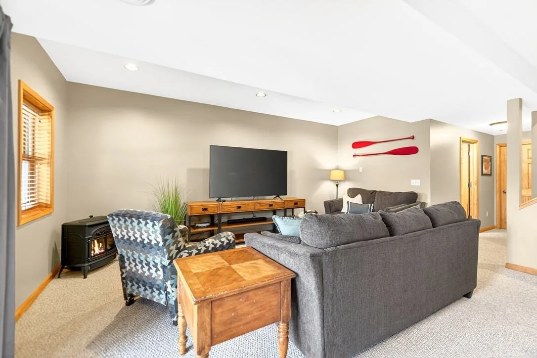 Lower level movie room with a sectional and a woodstove